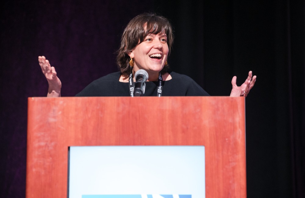 A woman speaks from behind a podium.