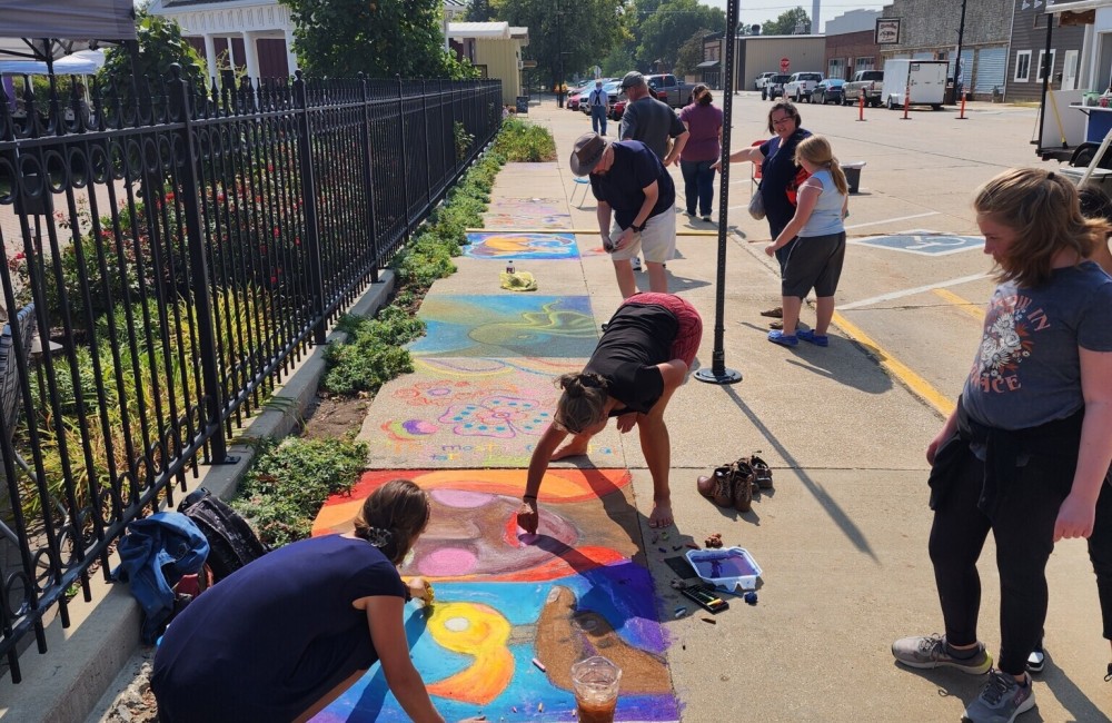 Photo of several artists creating sidewalk chalk art in Jefferson, Iowa.