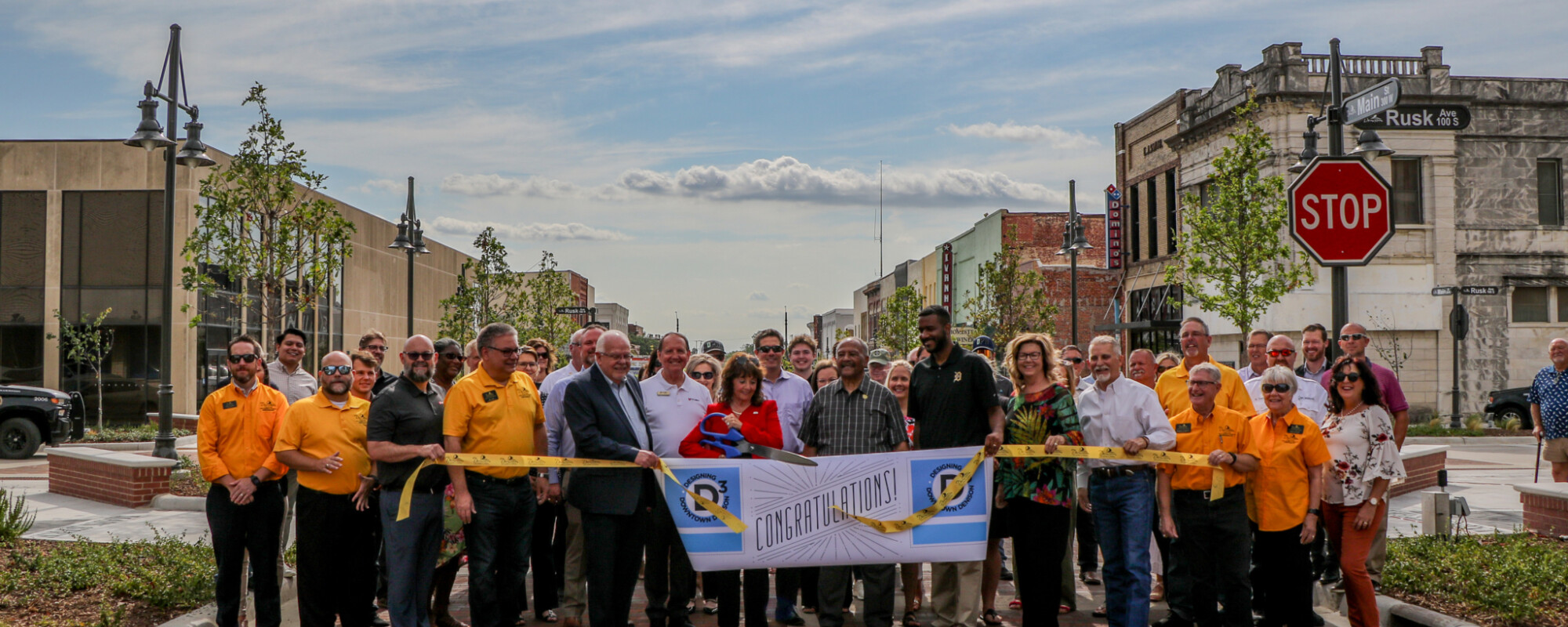 A large group of people holding a sign that says "congratulations." while standing in a newly finished streetscape