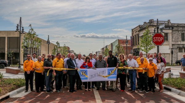 A large group of people holding a sign that says "congratulations." while standing in a newly finished streetscape
