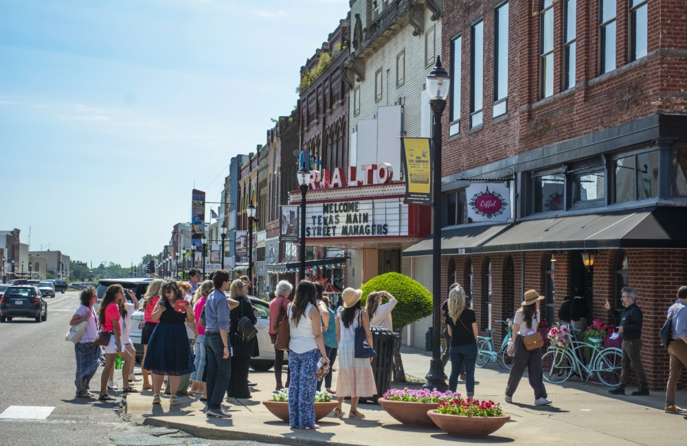 A small group of people tour a small retail block.