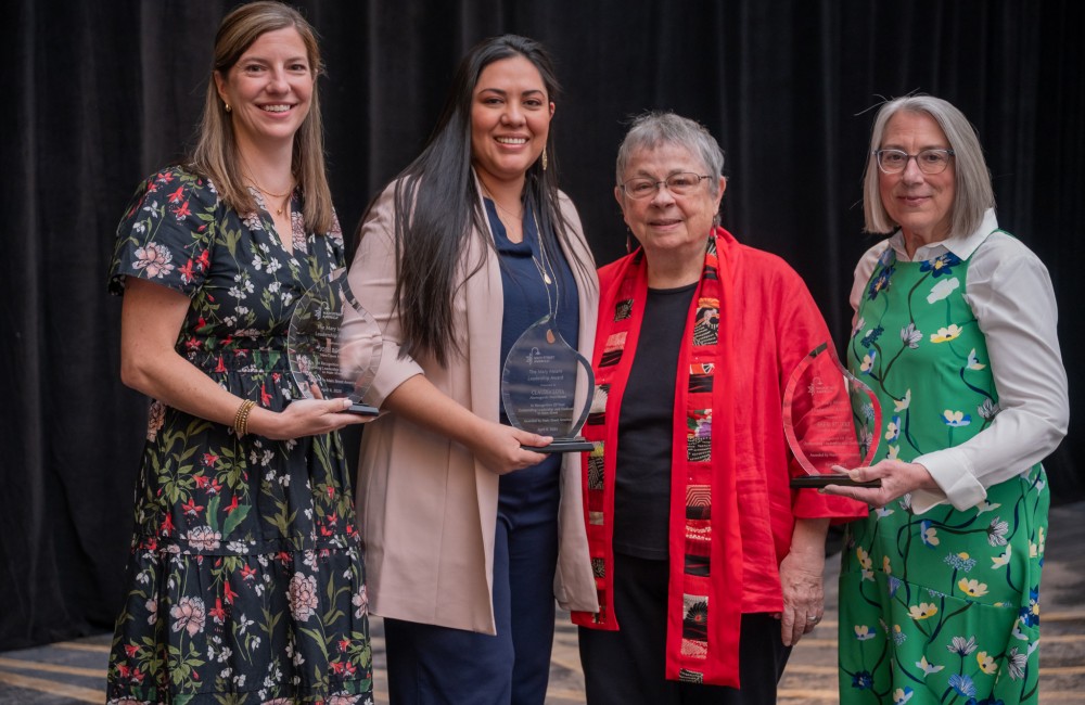 Four women, three holding awards, pose for a group photo.
