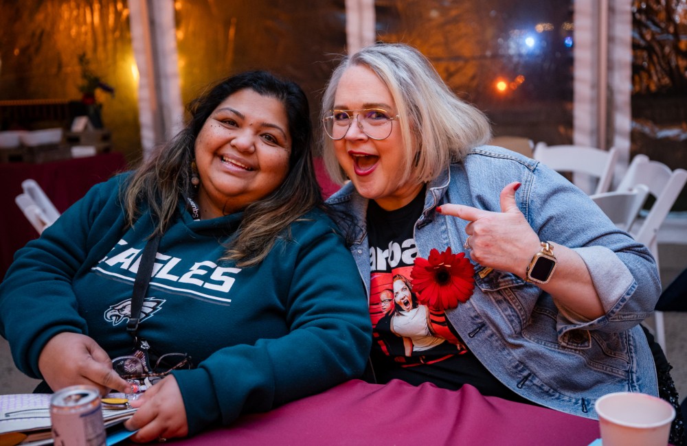 Two women smile while sitting at a table.