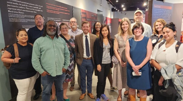 A large group of people posing for a photo in front of a display in a museum