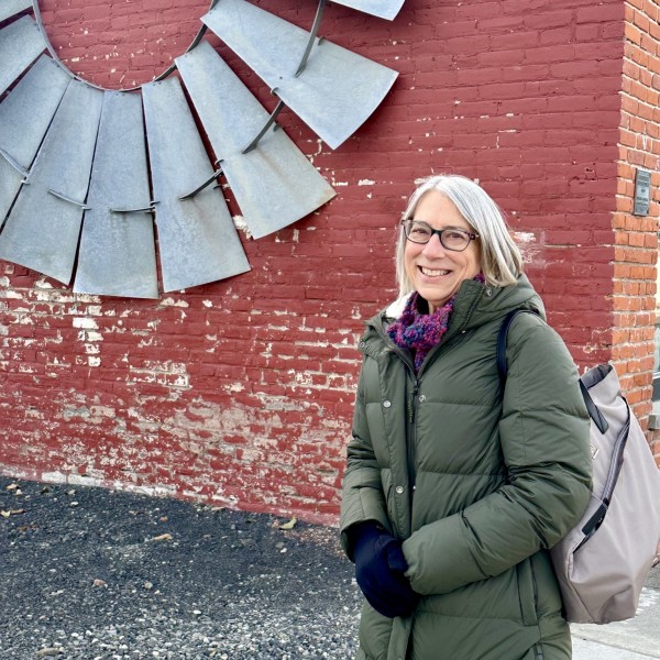 Headshot of woman standing in front of brick wall.
