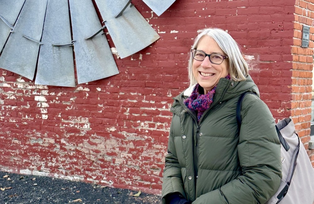 Headshot of woman standing in front of brick wall.