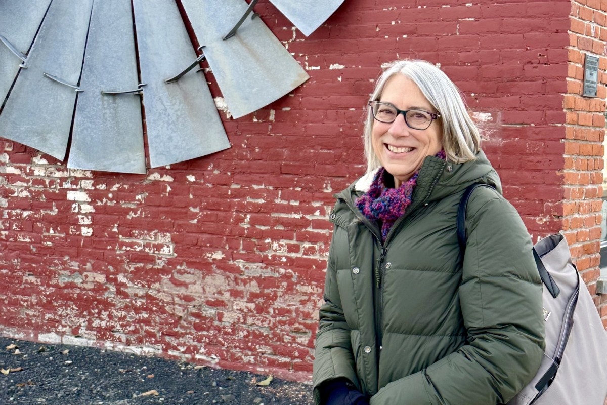 Headshot of woman standing in front of brick wall.