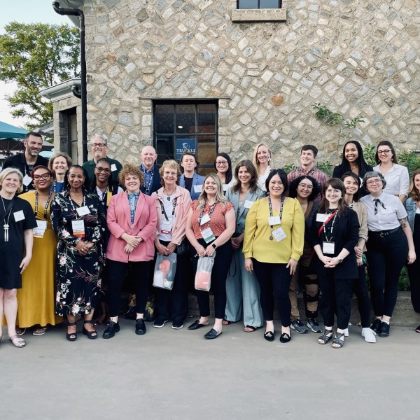 Large group of people pose for a photo in a courtyard.