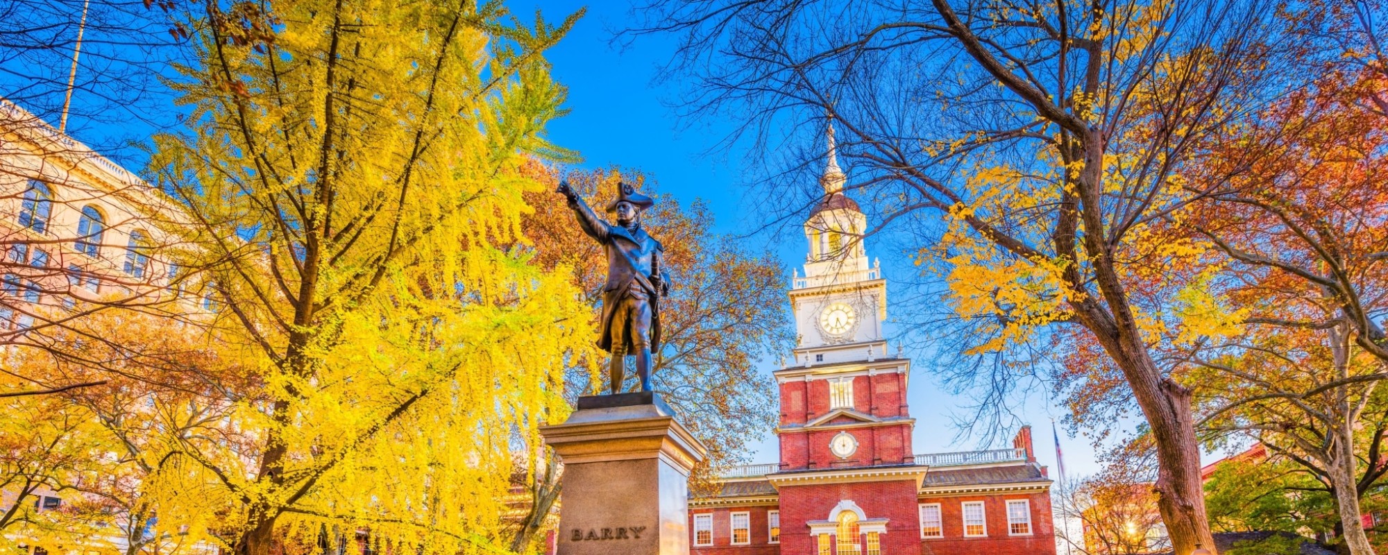 Bronze statue on a tall pedestal with Independence Hall in the background.