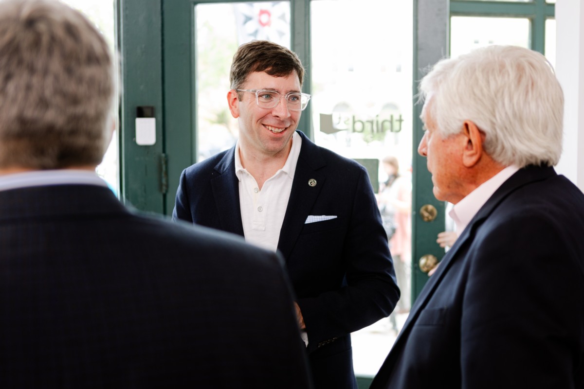 Three men in business suits converse.
