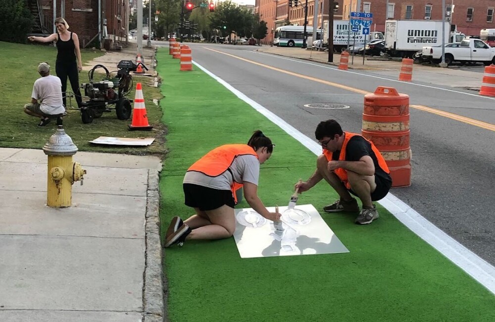 Volunteers work to paint a sign.