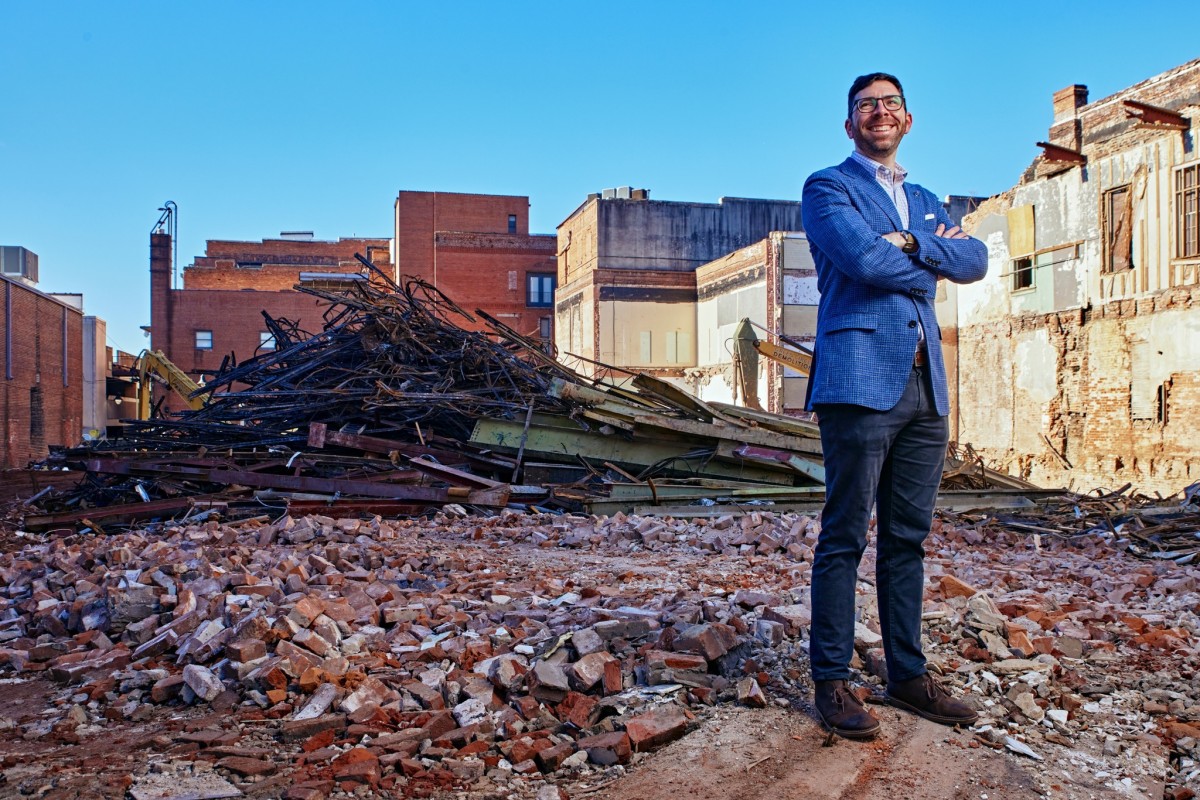 Man posing in front of a recently demolished building.