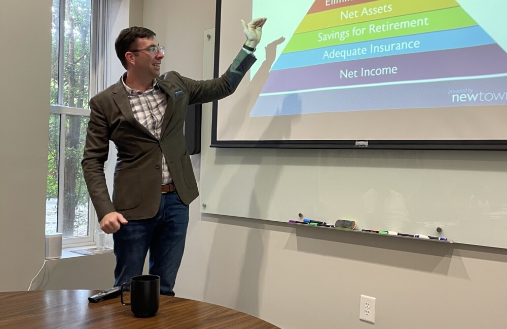 Man presents in front of a projector screen.