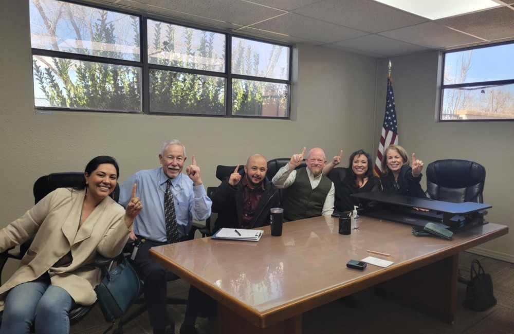 Small group poses at conference table.