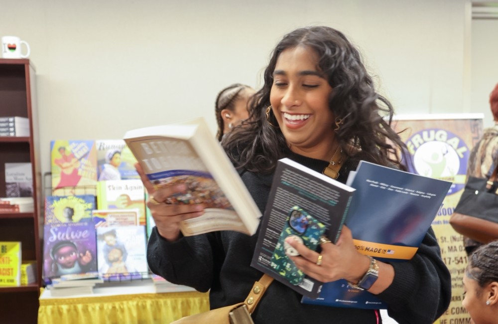 A woman smiles while selecting and previewing books at a pop-up bookshop.