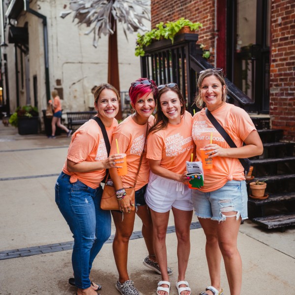 Three woman standing in orange matching shirts in Marion, Iowa.