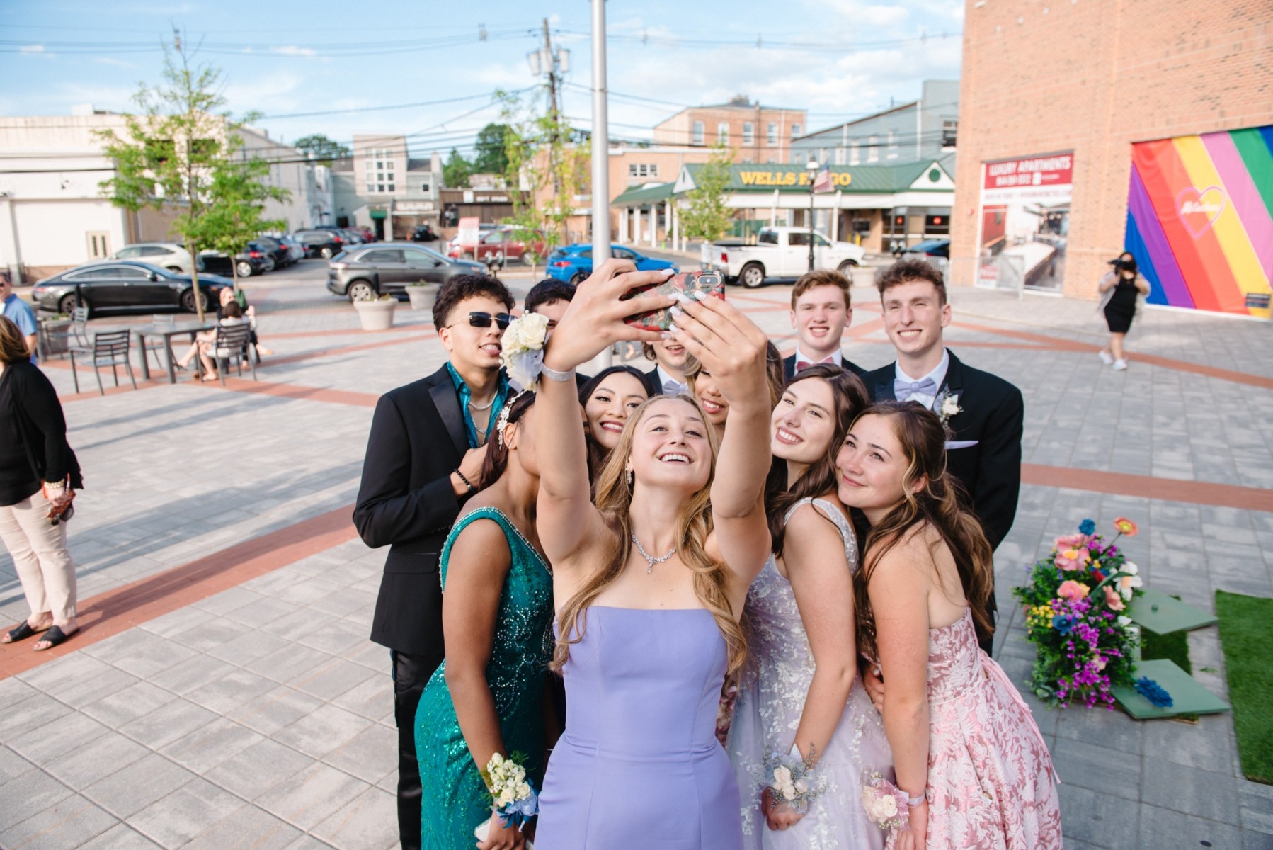 A group of teens in prom dresses poses for a selfie