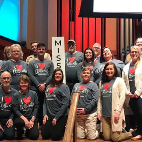 A large group of people wear matching shirts while posing for a group photo.