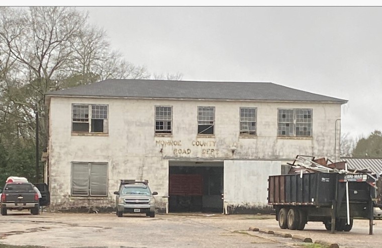 Exterior of a deteriorated two-story building with broken windows and a crumbling facade.