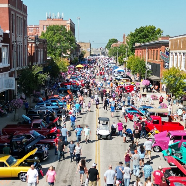 A busy street fair with vintage cars in a historic downtown on a sunny day