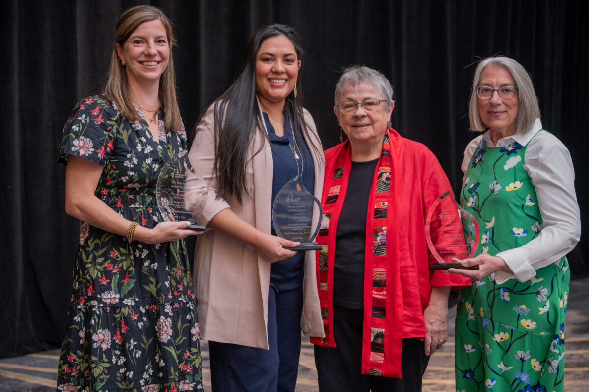 Four women pose for a group photo, three hold awards.