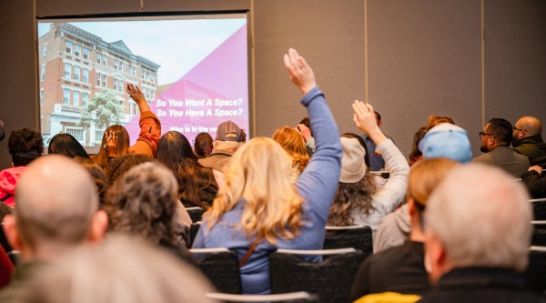 People attending a presentation raise their hands.