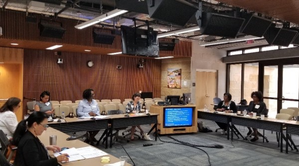 A group of people sit around tables in a board room. National League of Cities meeting in Austin, Texas.