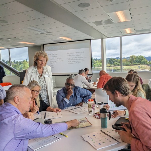 People are engaged in active discourse while gathered around a table.