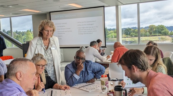 People are engaged in active discourse while gathered around a table.