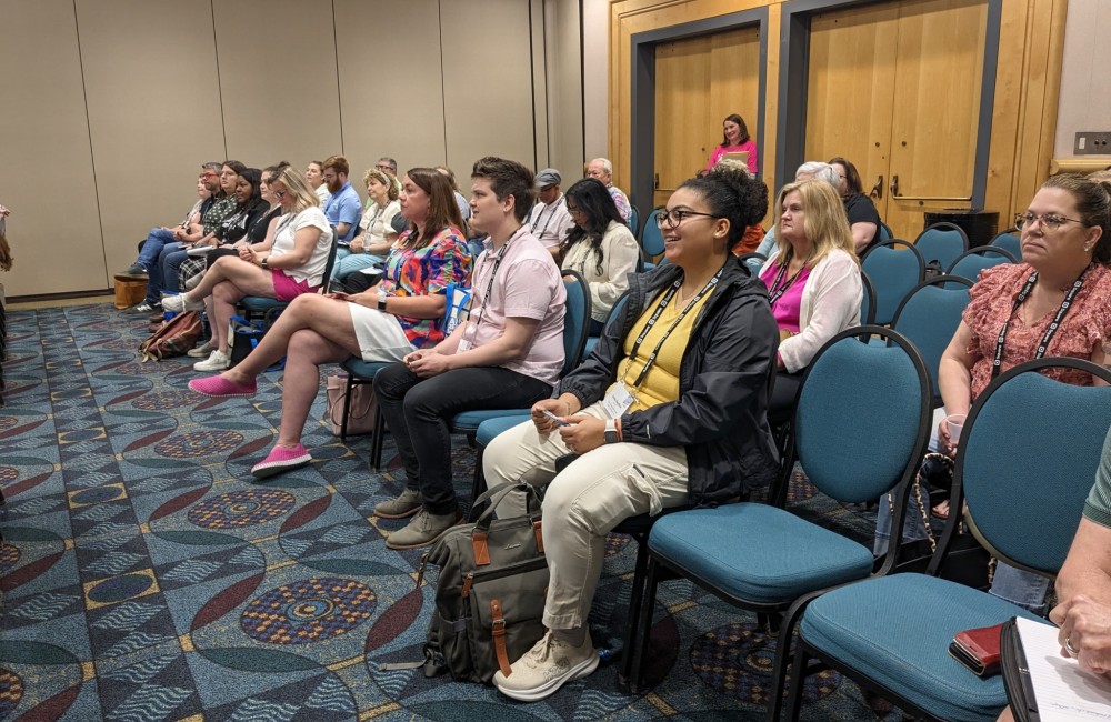 People seated in chairs and listening to a presentation.