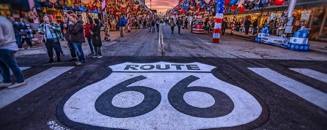 Large route 66 sign street art on the pavement outside a bustling street market