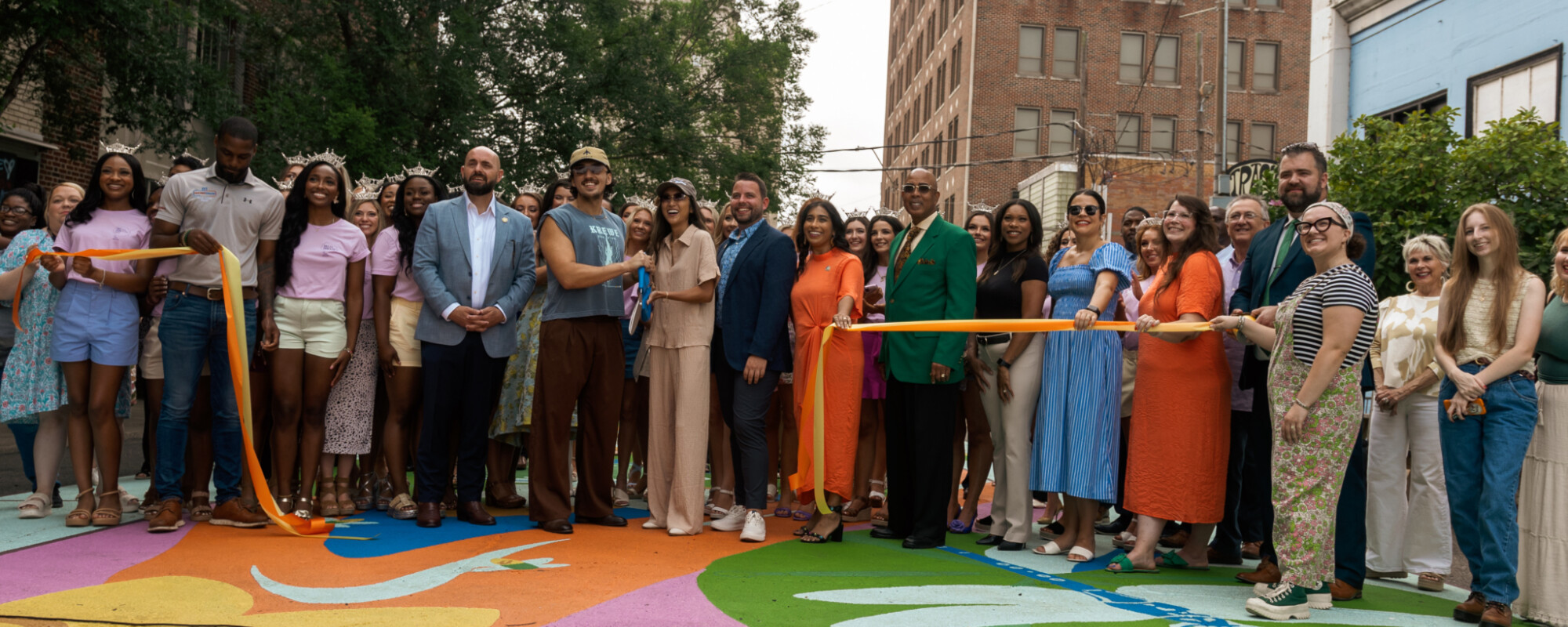 A large group of people participating in a ribbon cutting for colorful street art