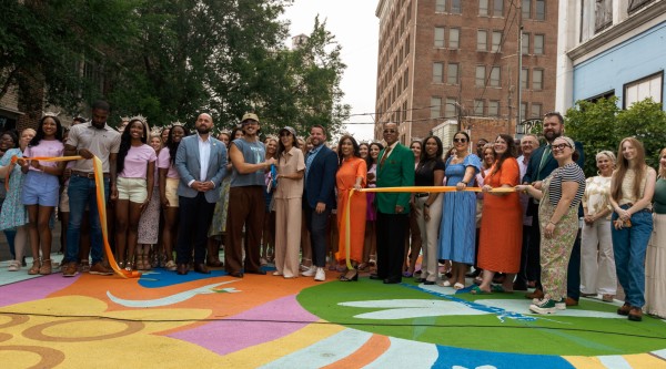 A large group of people participating in a ribbon cutting for colorful street art