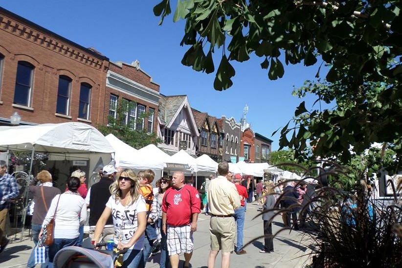 A woman pushing a stroller walks among a crowd at a downtown street festival