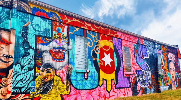 Brightly colored mural on the exterior of a building; the mural features the word "TULSA" surrounded by elements depicting Tulsa's diverse cultural heritage.