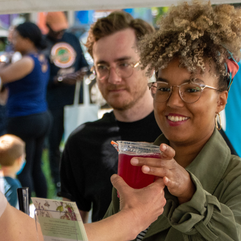 A vendor hands a beverage to a customer.
