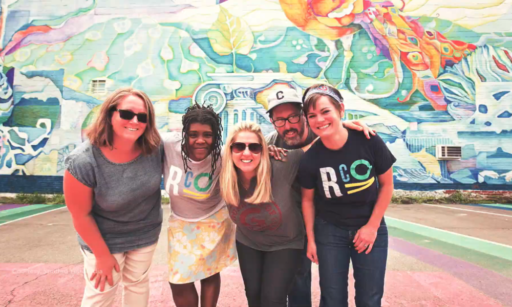 Covington, Kentucky staff members stand in front of a mural.
