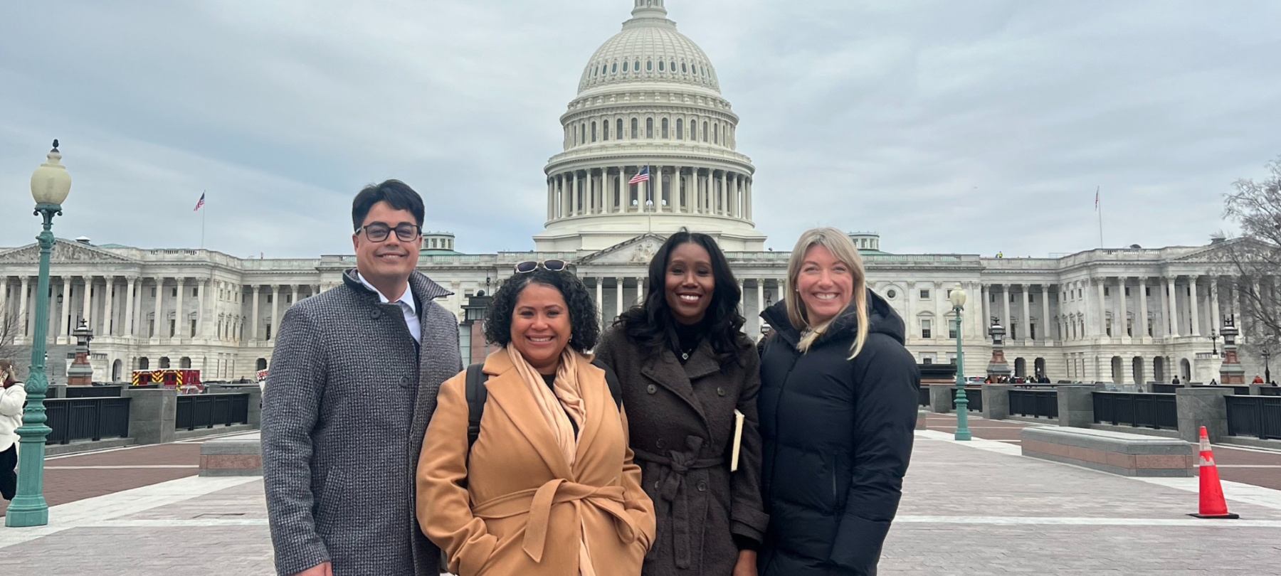 Four people posing for a photo in front of the Capitol building