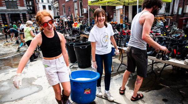 Two girls carrying a large bucket during floor cleanup